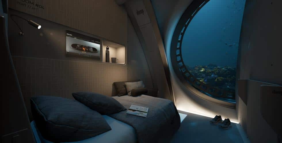 Lit et panneau électronique ressemblant à une télévision à l'intérieur d'un habitat subaquatique, avec une fenêtre offrant une vue sur la vie marine extérieure