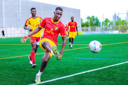 Le football en Afrique : au-delà du sport Match de football plein d'action avec des joueurs en uniformes vibrants sur un terrain vert.