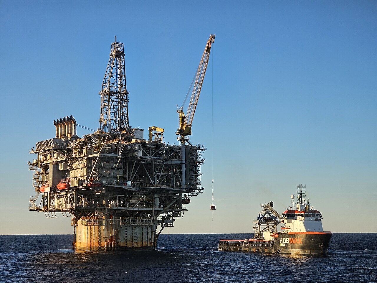 Des techniciens passent d'une plateforme pétrolière en mer à un navire de ravitaillement, illustration du secteur pétrolier et gazier